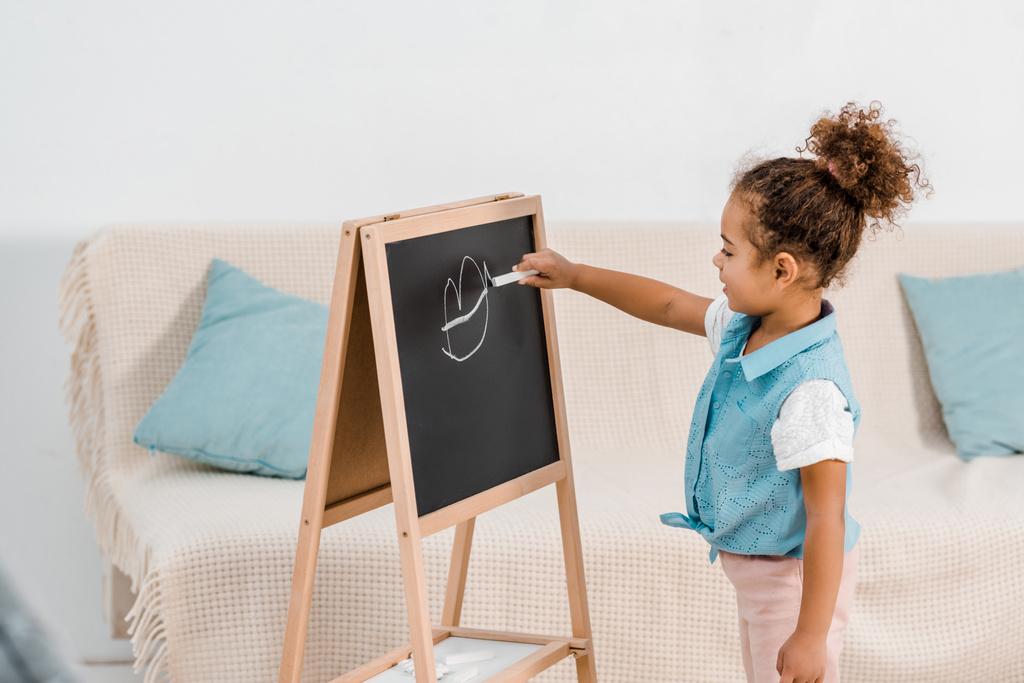 aranyos afro-amerikai gyermek állandó, és a rajz a chalkboard  - Fotó, kép