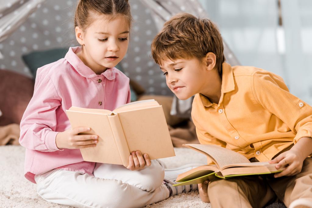 suloiset lapset istuvat matolla ja lukevat kirjoja yhdessä
   - Valokuva, kuva