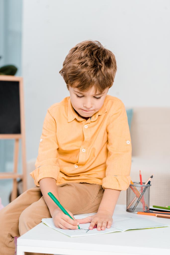 niño pequeño enfocado escribiendo y estudiando en casa
 - Foto, imagen