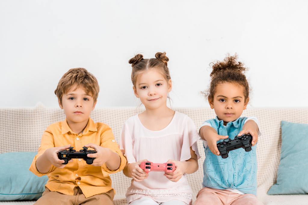 Miúdos bonitos jogando videogame com joysticks e olhando para a câmera
 - Foto, Imagem