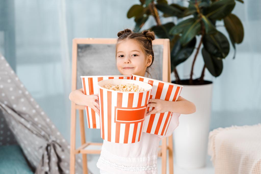 słodkie małe dziecko trzymając pola z popcornu i uśmiecha się do kamery - Zdjęcie, obraz
