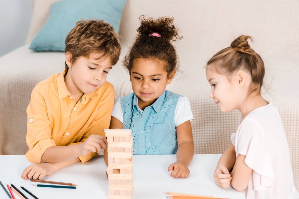 lindos niños felices construyendo torre de bloques de madera en la mesa
 - Foto, Imagen