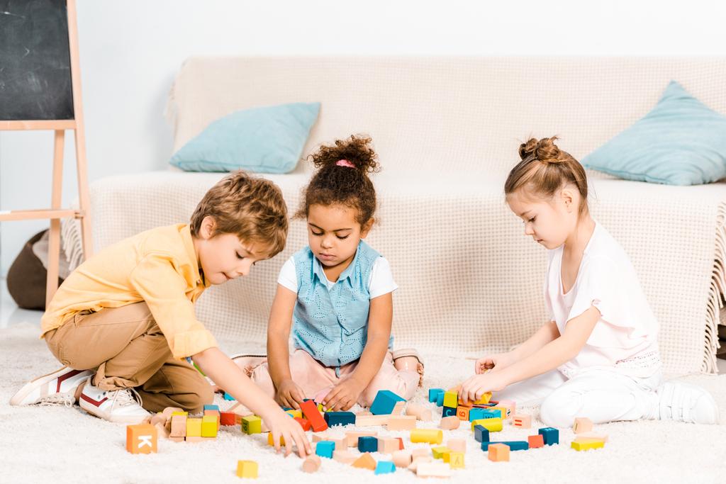 lindos niños pequeños jugando con cubos de colores en la alfombra
   - Foto, imagen