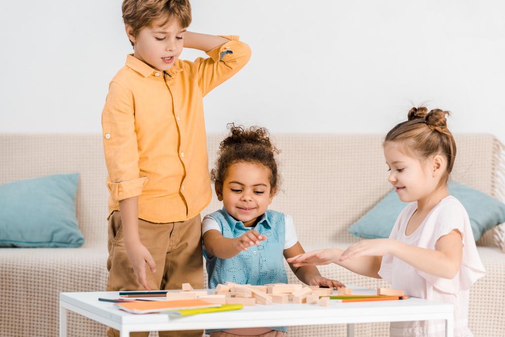 Urocza wieloetnicznym dzieci bawić się klockami drewnianymi na stole - Zdjęcie, obraz