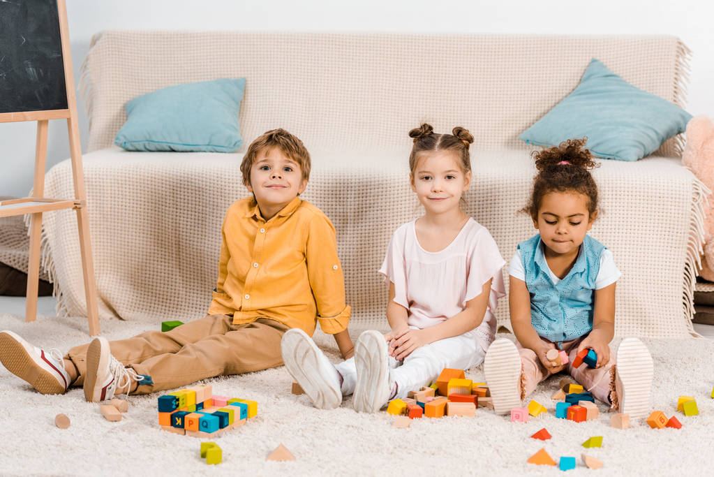 αξιολάτρευτο πολυεθνική παιδιά παιχνίδι με πολύχρωμους κύβους και να χαμογελά στη φωτογραφική μηχανή  - Φωτογραφία, εικόνα