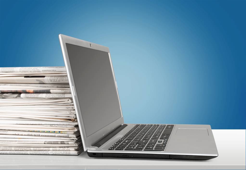 Стопка газет и современный ноутбук
 - Фото, изображение