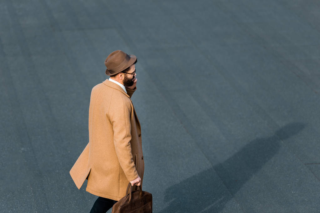 vue latérale de l'homme d'affaires en manteau beige parlant sur smartphone
 - Photo, image