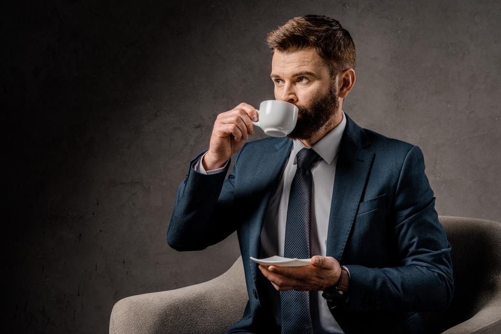 magabiztos üzletember kávét iszik, és a gazdaság csészealj - Fotó, kép