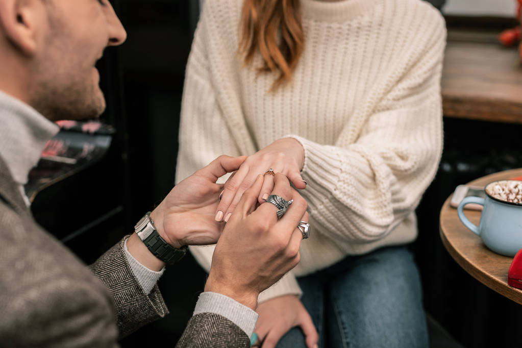Mann legt einen Ring an den Finger seiner Partnerin - Foto, Bild