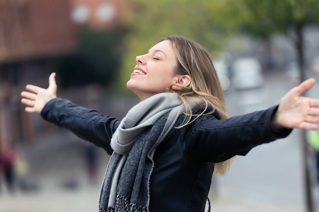 若い女性は新鮮な空気を呼吸を笑顔と街で腕を上げるのショット. - 写真・画像