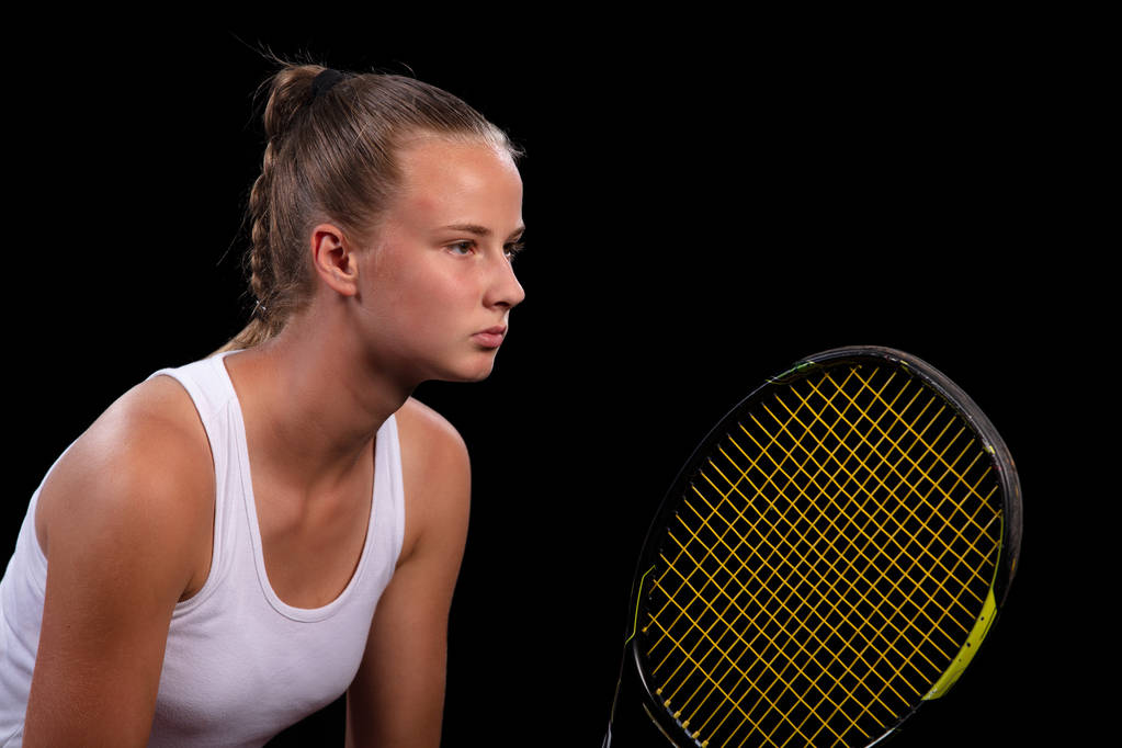 πορτρέτο του όμορφη γυναίκα που παίζει τένις εσωτερική. απομονώνονται σε μαύρο. - Φωτογραφία, εικόνα