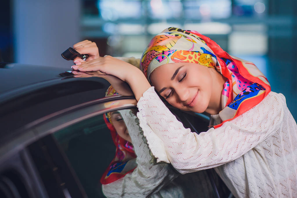propiedad y el concepto de la gente - mujer musulmana en hijab con la llave del coche sobre el fondo del espectáculo de coches. mujer feliz tomando la llave del coche del distribuidor en el espectáculo auto o salón
 - Foto, Imagen
