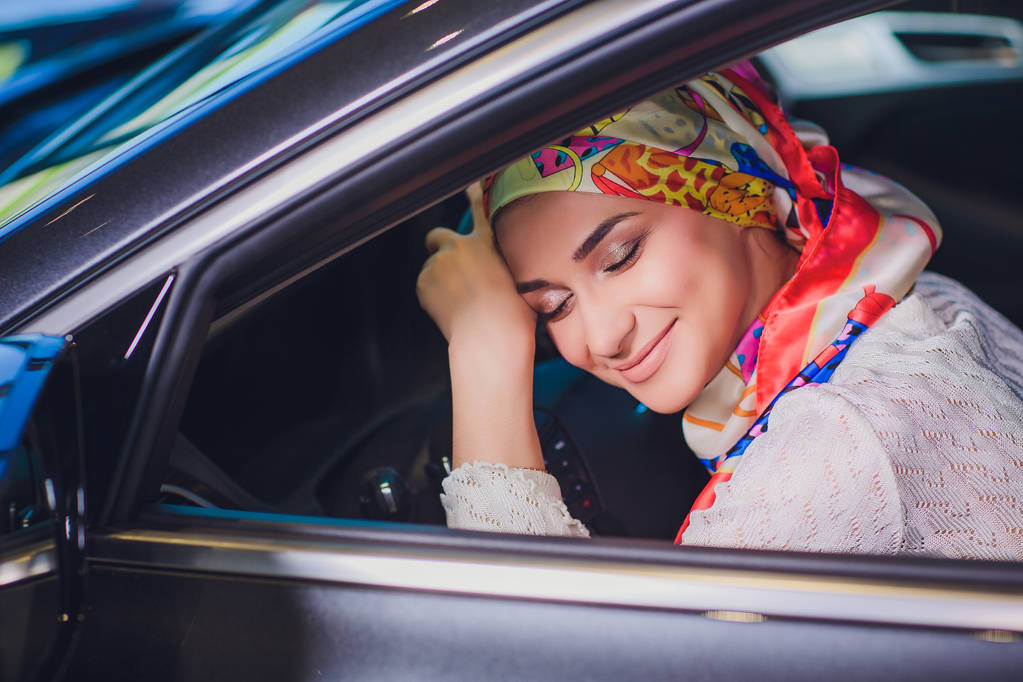 property and people concept - muslim woman in hijab with car key over car show background. happy woman taking car key from dealer in auto show or salon - Foto, Bild