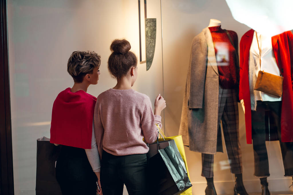 Dos mujeres de pie frente a la boutique colección de mujeres, vista trasera. - Foto, Imagen