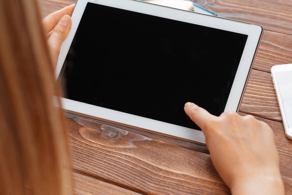 woman holding blank tablet device over a wooden workspace table - Photo, Image