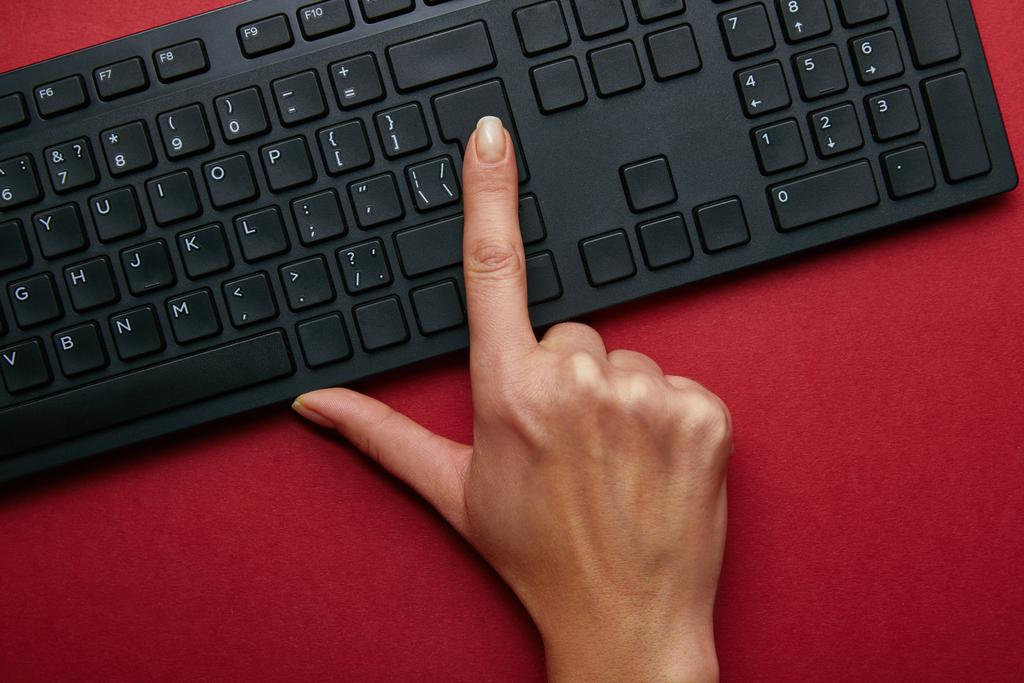 Widok z góry kobiety naciśnięcie przycisku na klawiaturze komputera czarny na czerwonym tle  - Zdjęcie, obraz