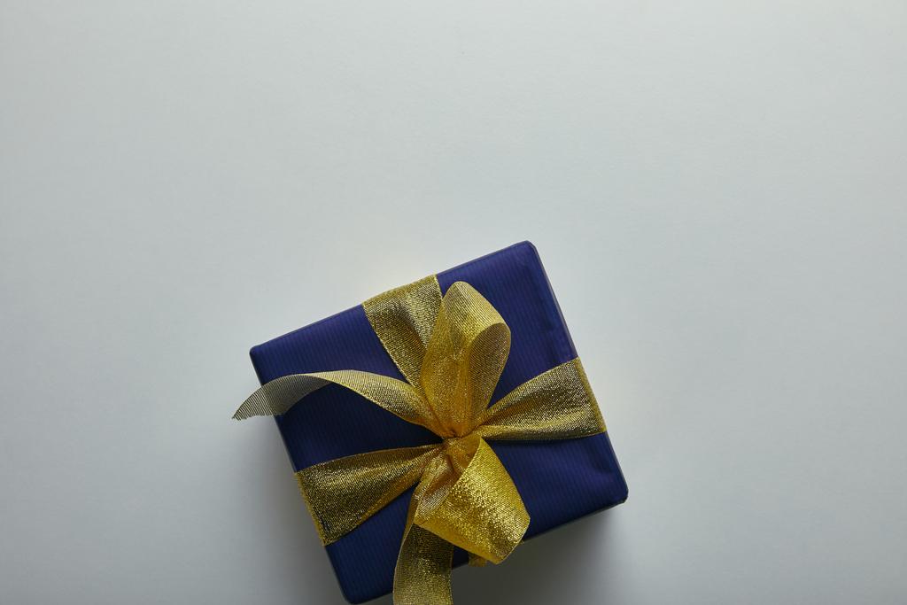 Felülnézet ajándék csomagolva kék csomagoló papírt sárga szalaggal, a szürke háttér  - Fotó, kép