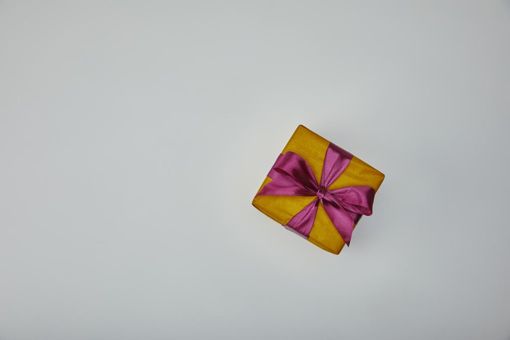 Vue du dessus du cadeau enveloppé avec ruban violet isolé sur fond gris
  - Photo, image