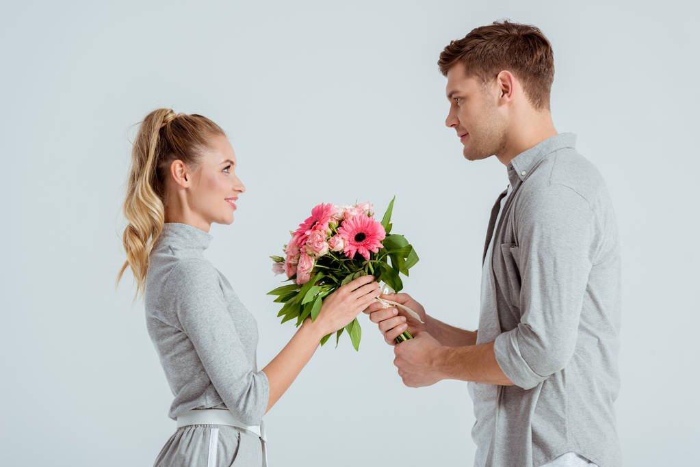 bonito homem dando rosa buquê de flores para mulher isolado no cinza
 - Foto, Imagem