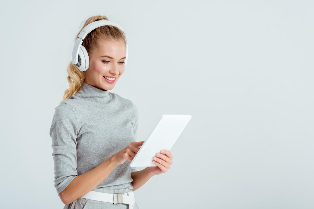 красива жінка в навушниках слухає музику і використовує цифровий планшет ізольовано на сірому
 - Фото, зображення