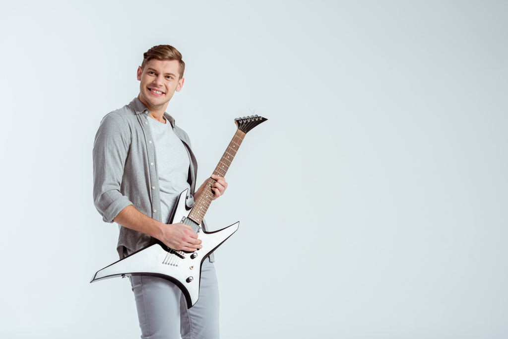 nadšený, pohledný muž v šedém oblečení hrát elektrická kytara izolované Grey - Fotografie, Obrázek