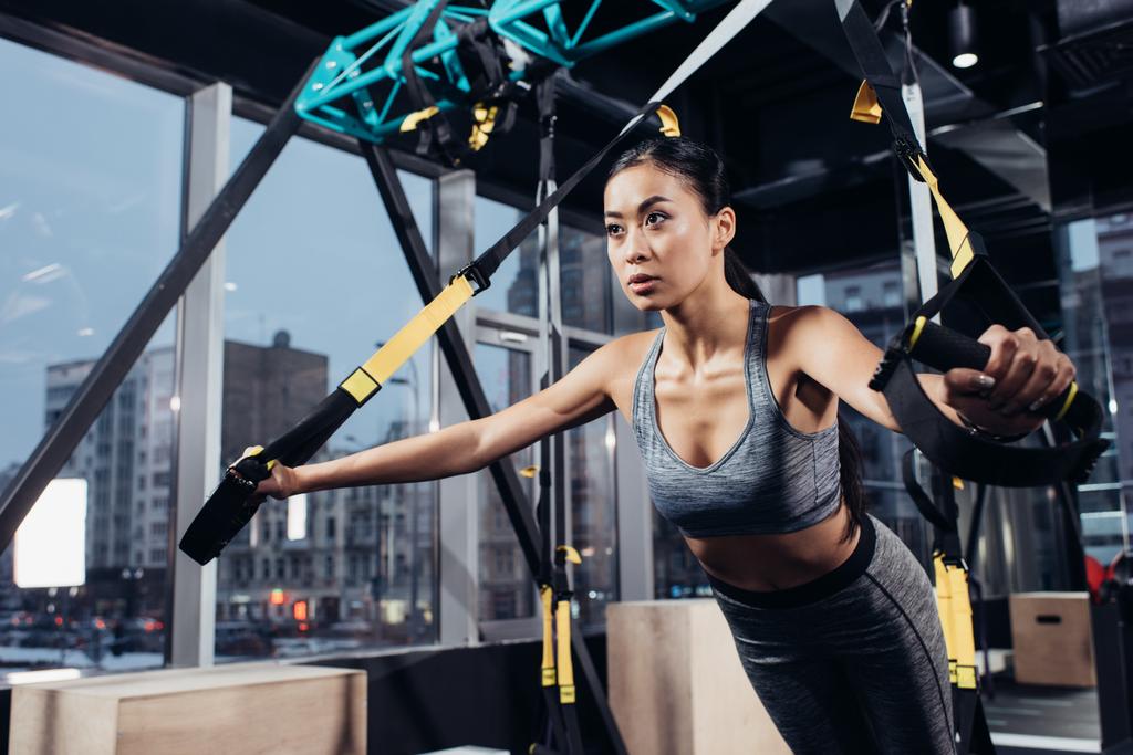 attractive asian girl training with resistance bands at gym - Photo, Image