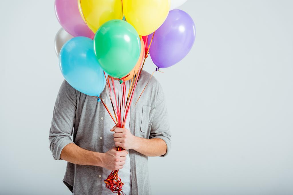 человек в серой одежде прячется за пучком разноцветных воздушных шаров с копировальным пространством на сером фоне
 - Фото, изображение