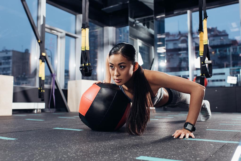 attraktive asiatische Mädchen machen Liegestütze mit Medizinball im Fitnessstudio - Foto, Bild