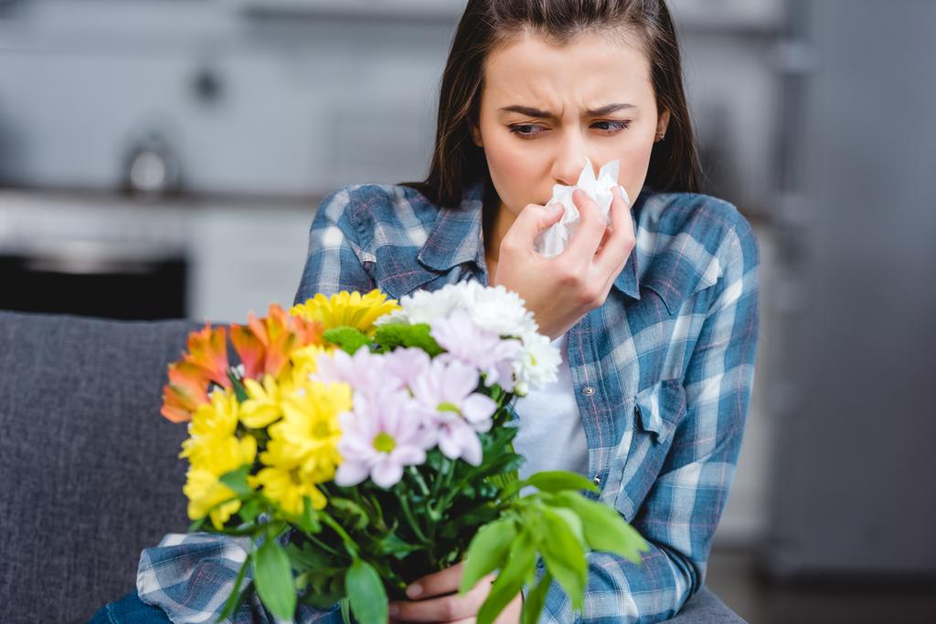 girl with allergy holding facial tissue and looking at flowers  - Photo, Image