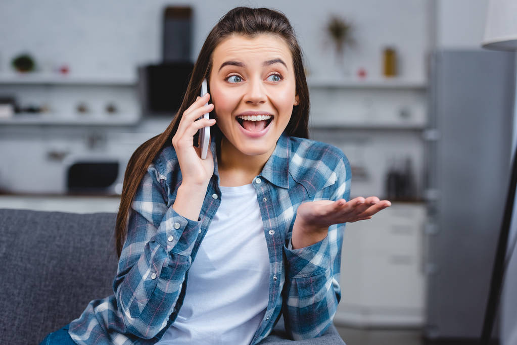 Veselá mladá žena mluví o smartphone, zatímco sedí doma - Fotografie, Obrázek