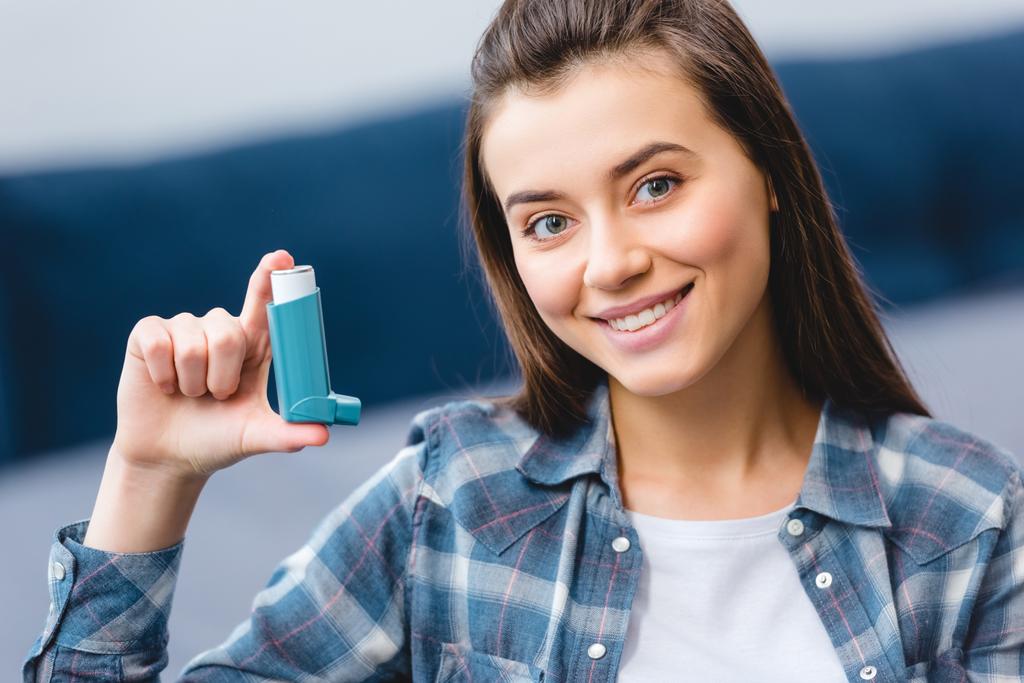 glückliche junge Frau mit Inhalator und lächelnd in die Kamera  - Foto, Bild