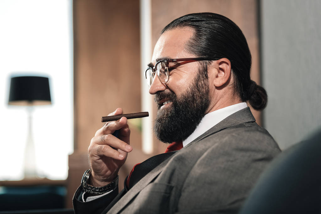 Bebaarde zakenman bril koelen terwijl roken sigaar - Foto, afbeelding