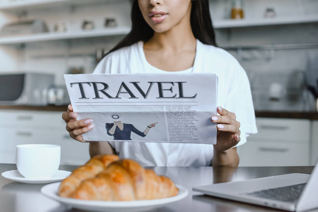 Oříznout obrázek dívky Smíšené rasy v bílém rouchu, čtení novin cestování v ráno v kuchyni - Fotografie, Obrázek