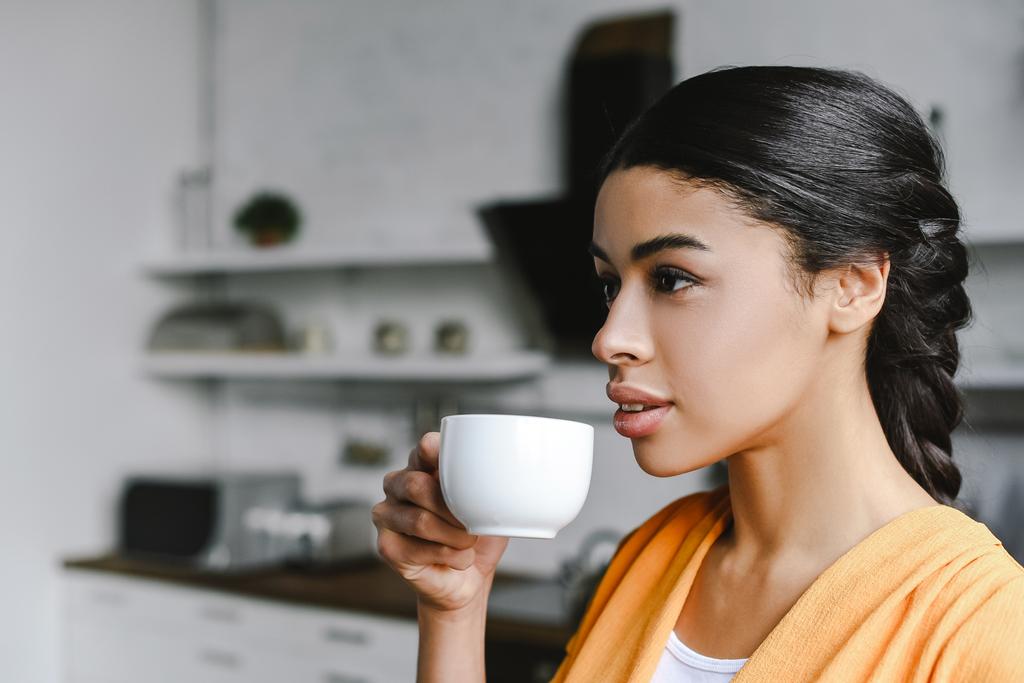 Porträt der schönen Mischlingshündin in orangefarbenem Hemd, die morgens in der Küche Kaffee trinkt - Foto, Bild