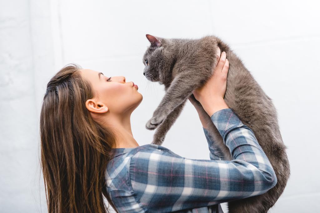 side view of beautiful girl holding cute british shorthair cat - Photo, Image