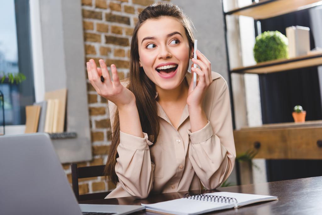 счастливая молодая деловая женщина разговаривает по смартфону во время работы в офисе
  - Фото, изображение