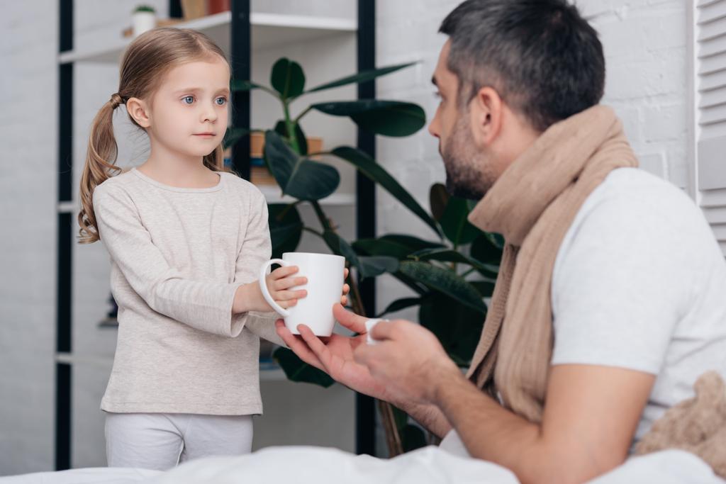 entzückende Tochter gibt kranken Vater im Schlafzimmer eine Tasse Tee - Foto, Bild
