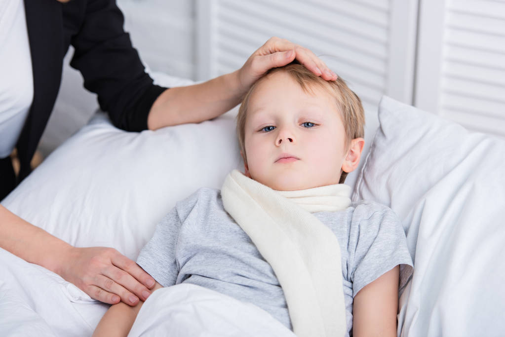 imagem cortada da mãe cuidando do filho doente e tocando sua testa no quarto
 - Foto, Imagem