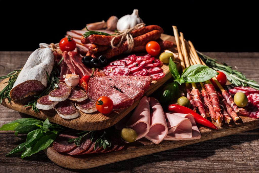 tábuas de corte com delicioso salame, salsichas defumadas, presunto e legumes em mesa rústica de madeira
 - Foto, Imagem