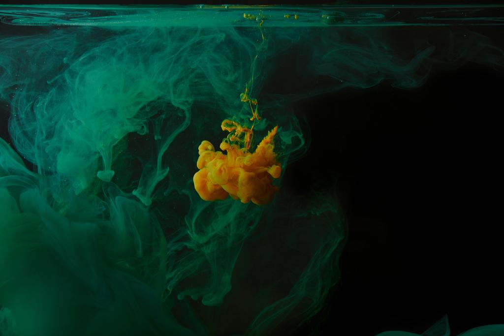 černé pozadí s zelené víry a oranžové cákanec barvy ve vodě - Fotografie, Obrázek