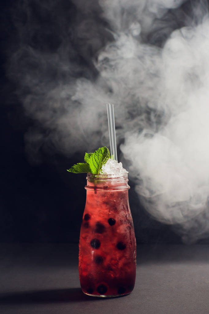 cóctel de ron oscuro y tormentoso con fresa contra humo de fondo
. - Foto, Imagen