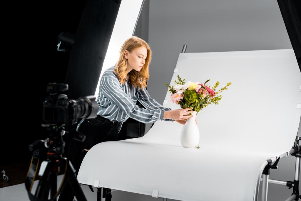 zbliżenie, aparat fotograficzny i młoda kobieta, układanie kwiatów w studio fotograficzne  - Zdjęcie, obraz