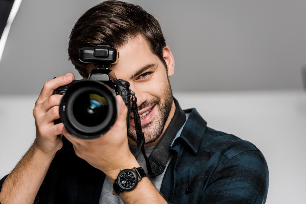 красивый счастливый молодой человек фотографирует с камерой в студии
  - Фото, изображение