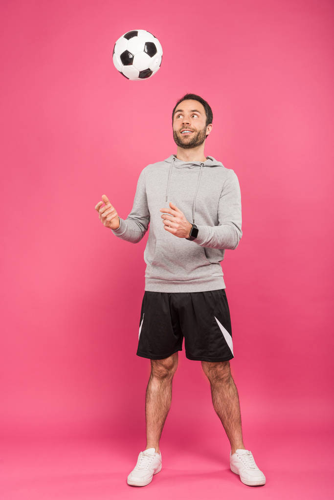 handsome sportsman throwing up soccer ball isolated on pink - Photo, Image