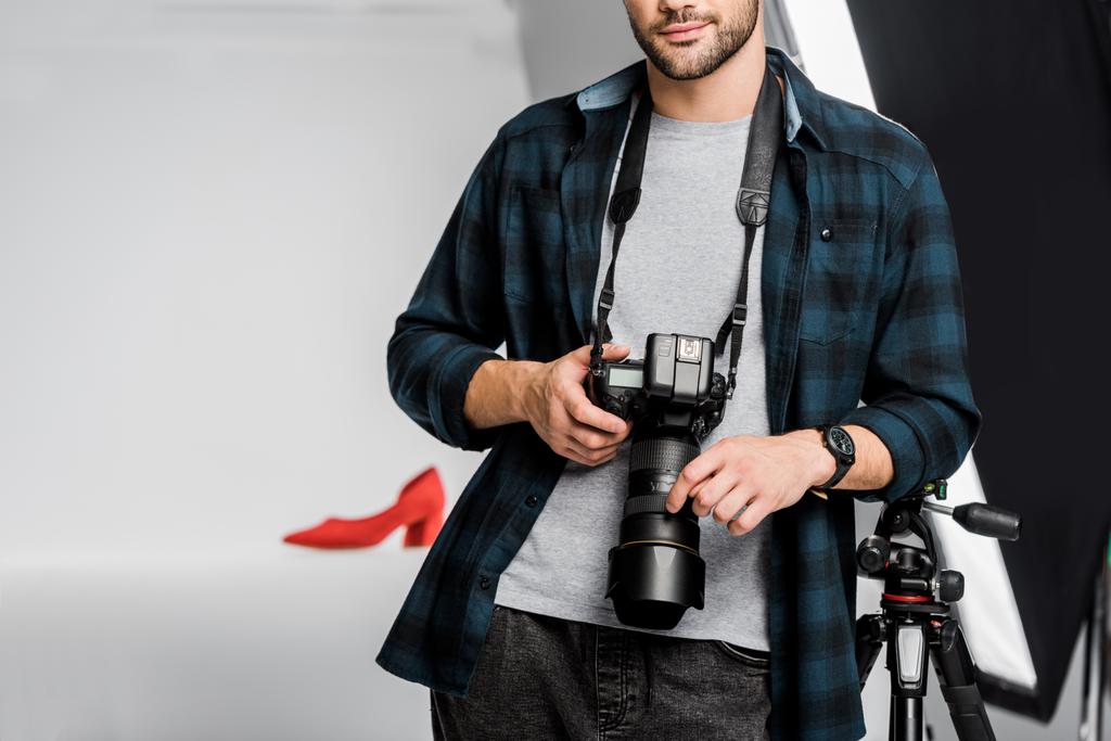 Oříznout záběr profesionálních mladý fotograf drží fotoaparát ve fotoateliéru  - Fotografie, Obrázek