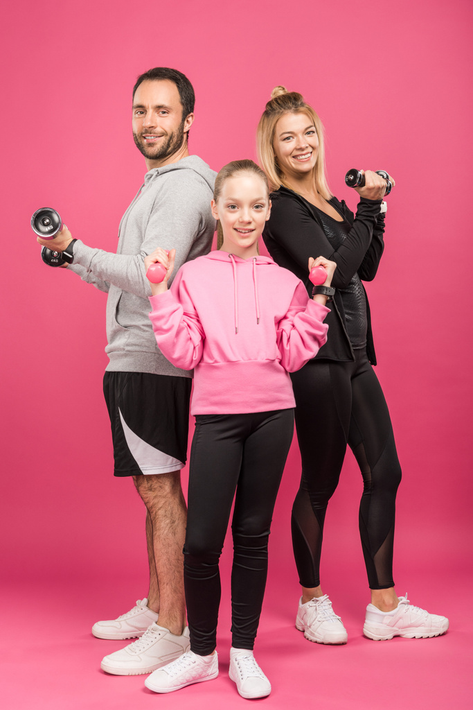 Sportliches Eltern-Tochter-Training mit Kurzhanteln, isoliert auf rosa - Foto, Bild