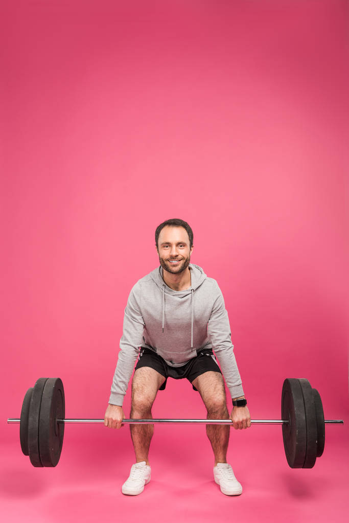 knappe sportman opheffing barbell, geïsoleerd op roze - Foto, afbeelding