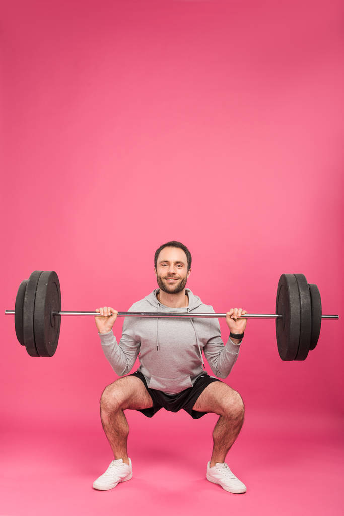athletic man training with barbell, isolated on pink - Photo, Image