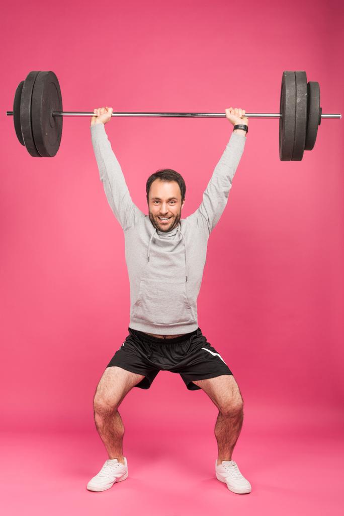 fuerte entrenamiento de deportista con barra, aislado en rosa
  - Foto, imagen