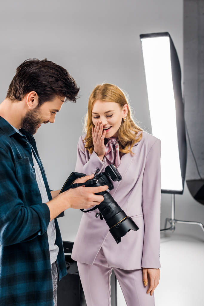 happy young photographer and model using photo camera together in studio   - Photo, Image
